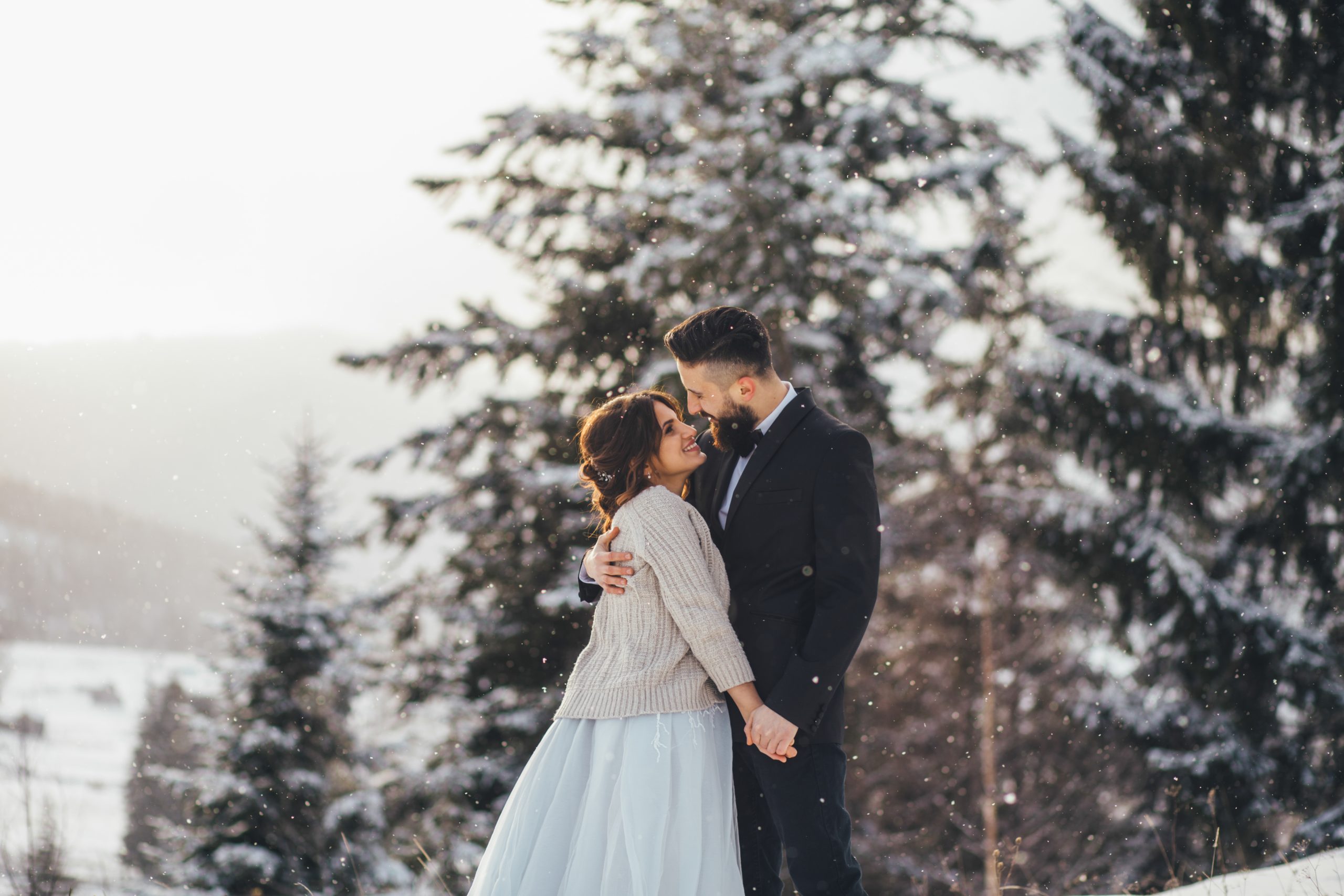Bearded man and his lovely bride pose on the snow in a magic win